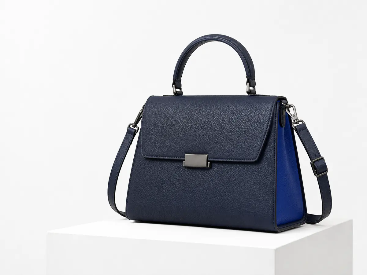 Navy pebbled leather handbag with silver clasp on a white pedestal