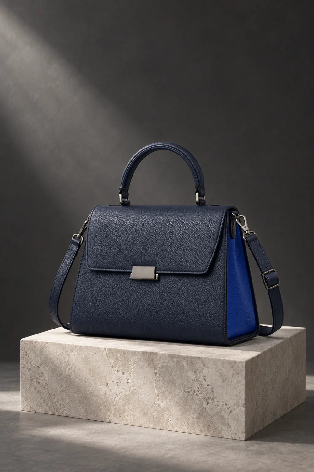 Complete navy handbag on a pale plinth in a charcoal photographic studio
