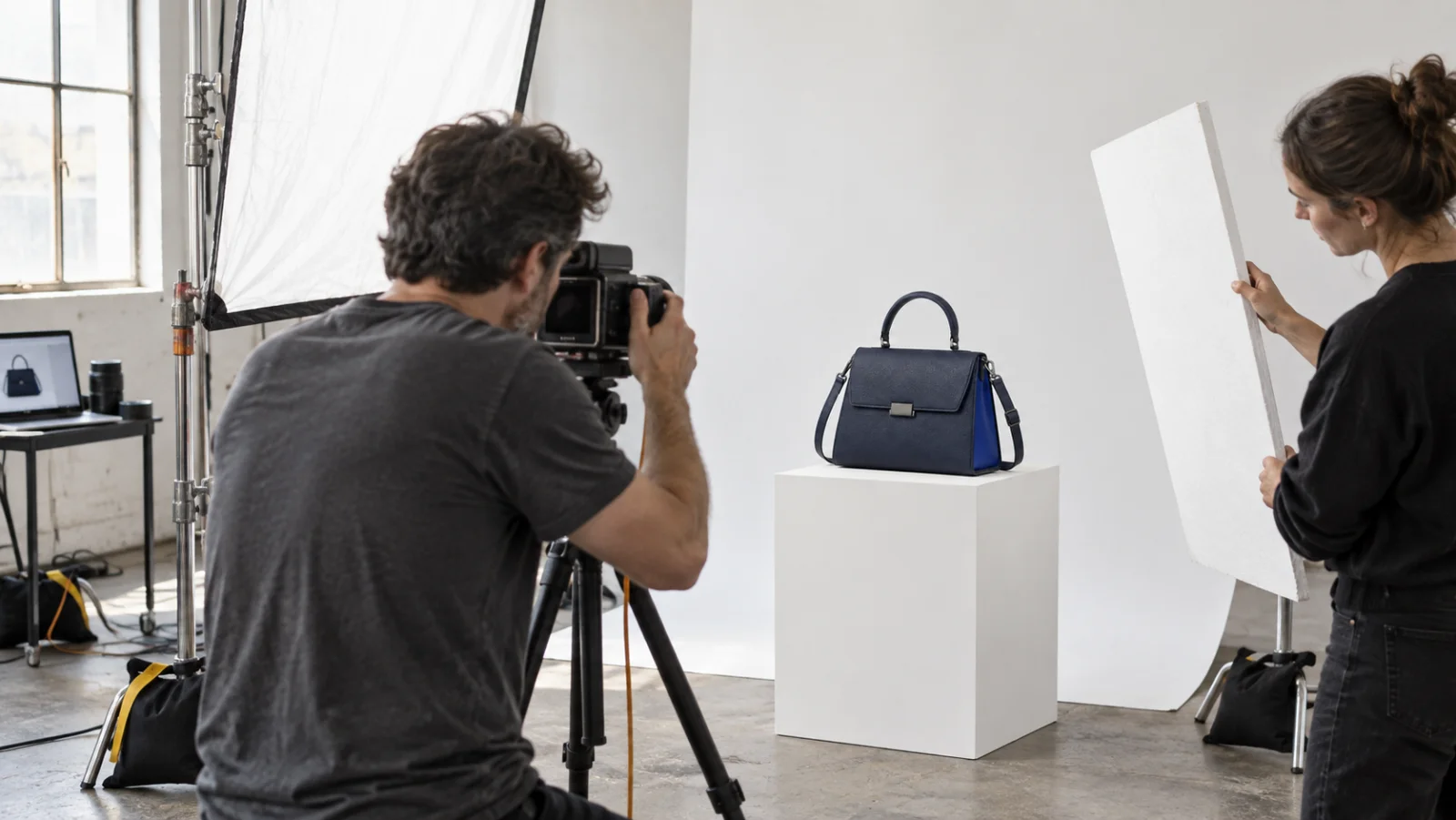 Conceptual studio setup: photographer, diffusion panel and reflector around the same navy bag